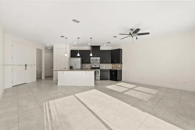 a large white kitchen with kitchen island a sink stainless steel appliances and cabinets