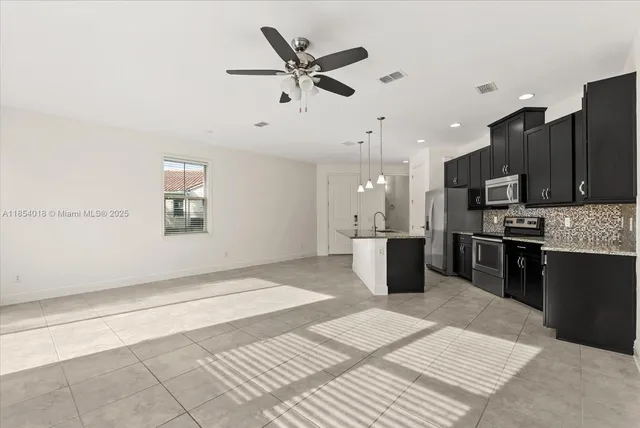 a kitchen with stainless steel appliances kitchen island granite countertop a refrigerator and a sink