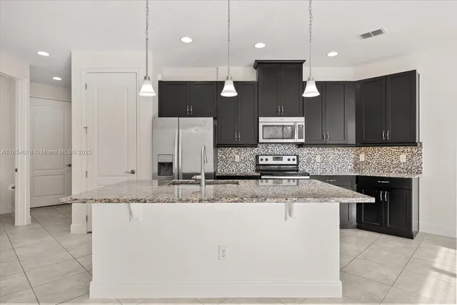 a large kitchen with granite countertop a sink a counter top space appliances and cabinets