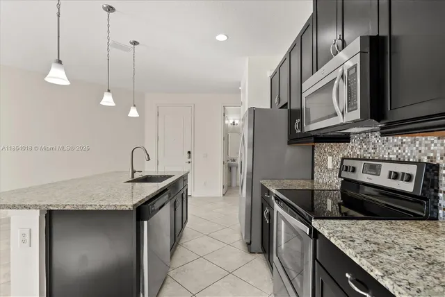 a kitchen with stainless steel appliances granite countertop a sink a stove and a refrigerator