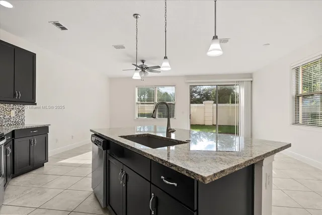 a kitchen with granite countertop stainless steel appliances a sink stove and cabinets