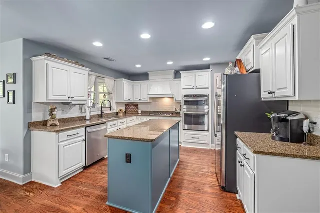 a kitchen with stainless steel appliances granite countertop a refrigerator and a stove top oven