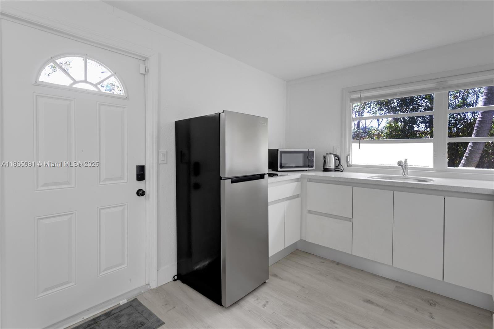 a kitchen with white cabinets and refrigerator
