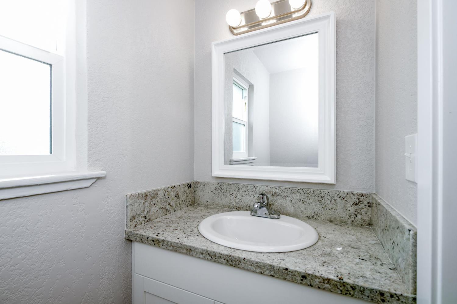 4031 East Pontiac Way Fresno, CA 93726 - Photo 20 of 46 a bathroom with a granite countertop sink and a mirror