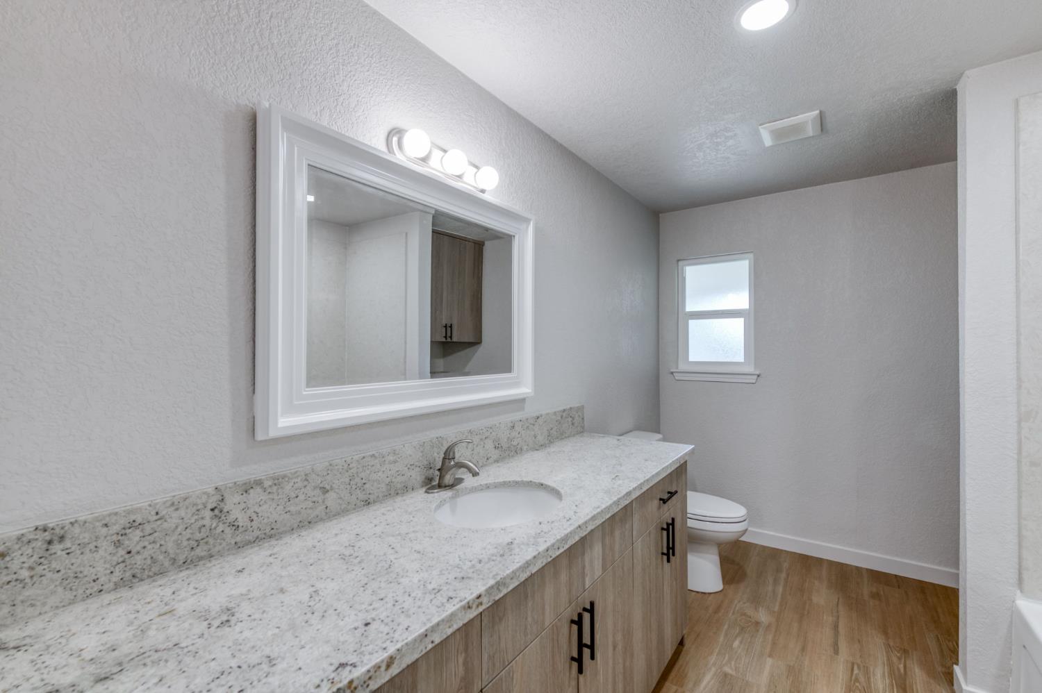 4031 East Pontiac Way Fresno, CA 93726 - Photo 22 of 46 a bathroom with a granite countertop sink and a mirror