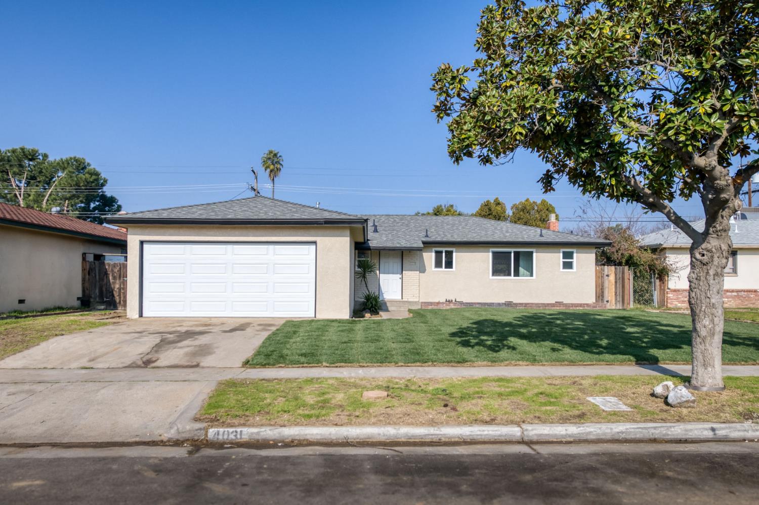4031 East Pontiac Way Fresno, CA 93726 - Photo 3 of 46 a front view of a house with a yard and garage