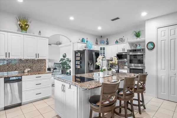 a kitchen with stainless steel appliances kitchen island granite countertop a table chairs and a refrigerator
