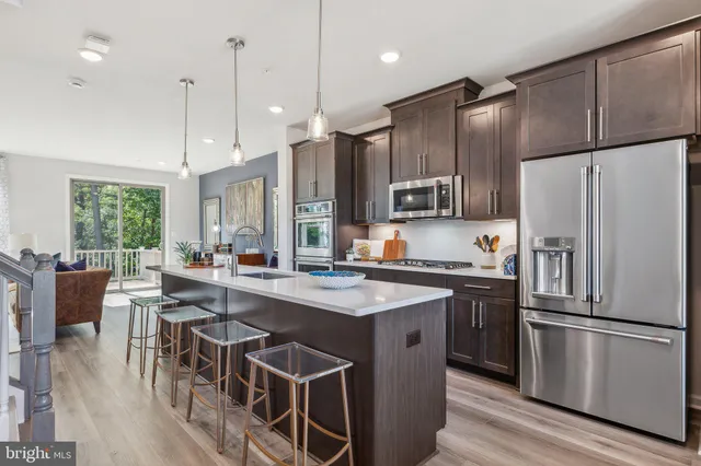 a kitchen with stainless steel appliances granite countertop a refrigerator a stove a sink a dining table and chairs with wooden floor