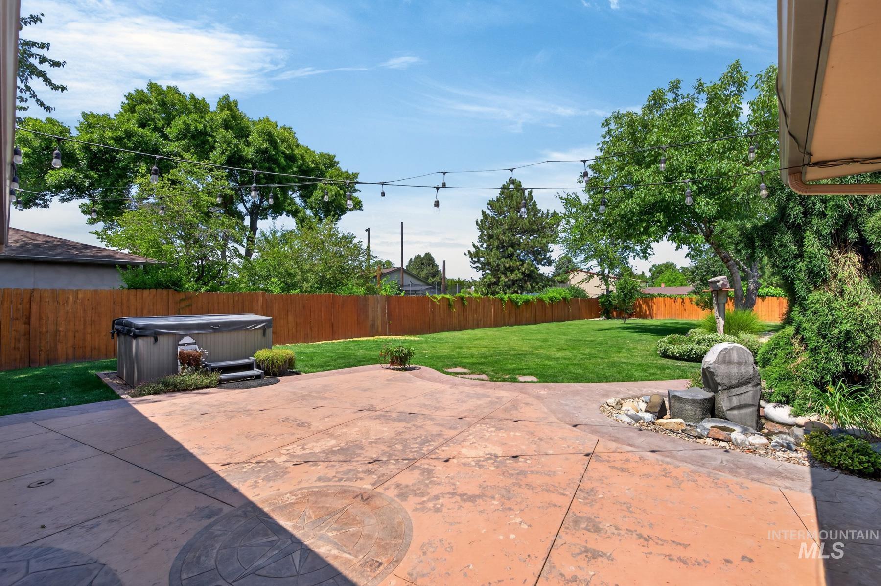 9622 Delaware Street Boise, ID 83709 - Photo 32 of 48 Spacious backyard featuring an expansive stamped concrete patio, a built-in hot tub, and a decorative water feature