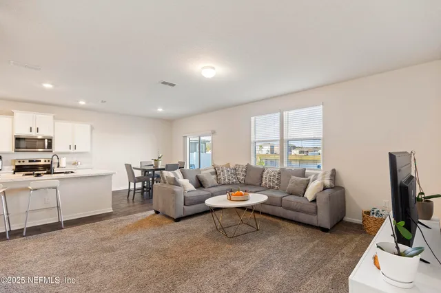 a living room with furniture flat screen tv and window