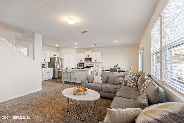 a living room with furniture kitchen and a large window