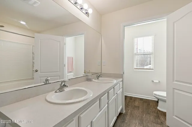 a bathroom with a sink double vanity granite and a toilet
