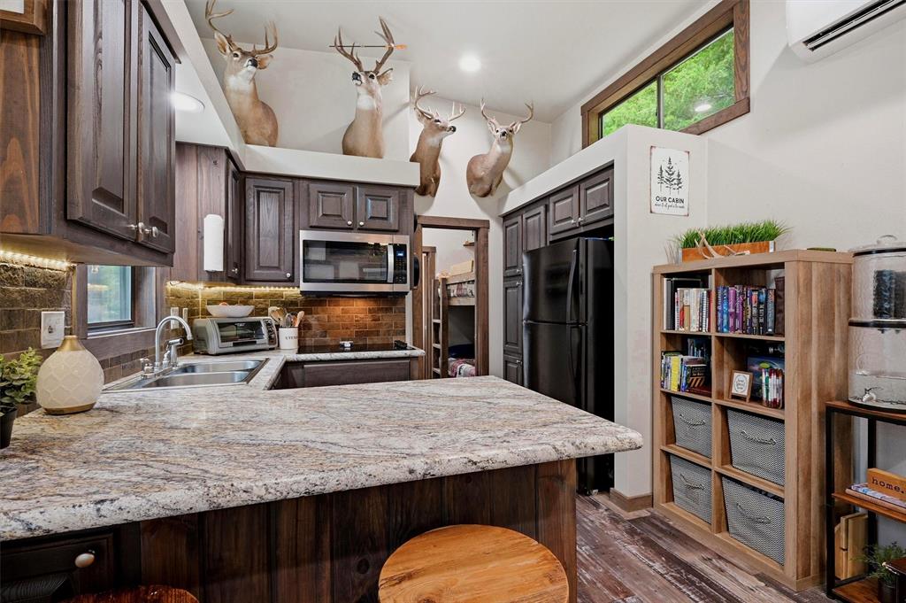 3958 Ranch Road Whitesboro, TX 76273 - Photo 15 of 40 Kitchen featuring granite-style countertops, wood-finish cabinetry, stainless steel microwave, and a tile backsplash