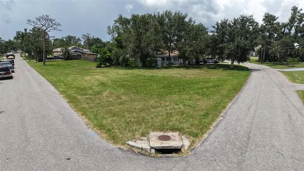 a view of a white house with a yard and trees in the background