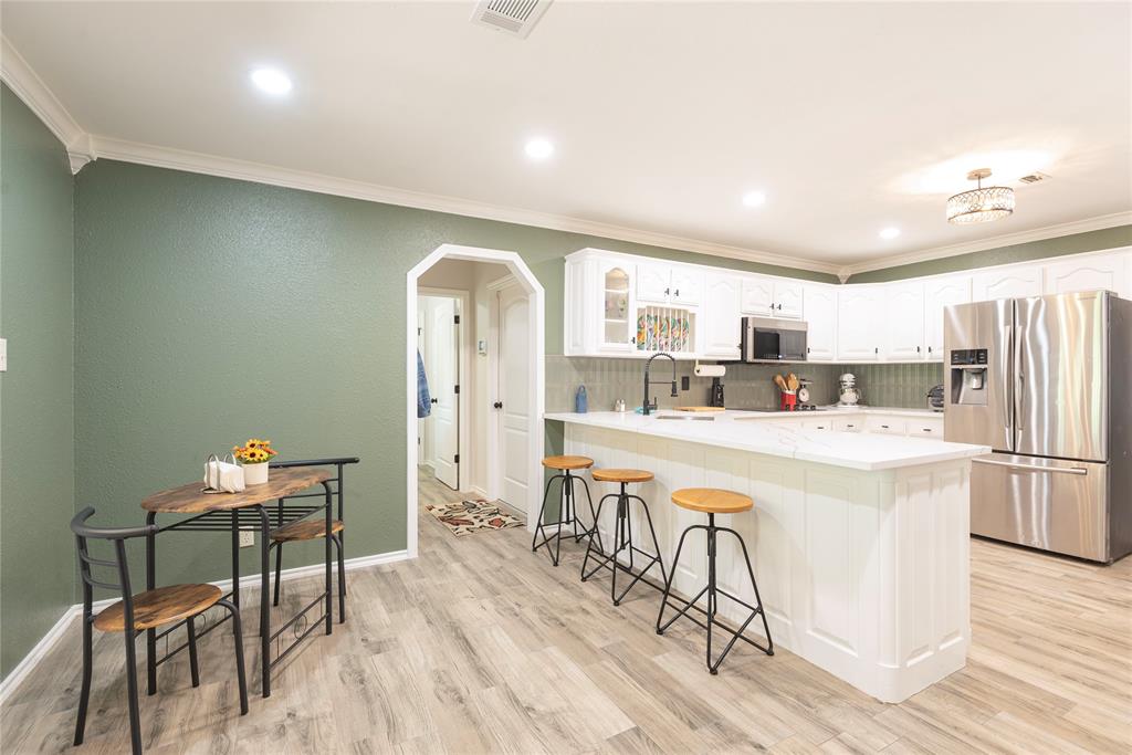 2020 Arbor Bend Road Bonham, TX 75418 - Photo 11 of 40 Kitchen featuring arched walkways, stainless steel appliances, glass insert cabinets, ornamental molding, and a peninsula
