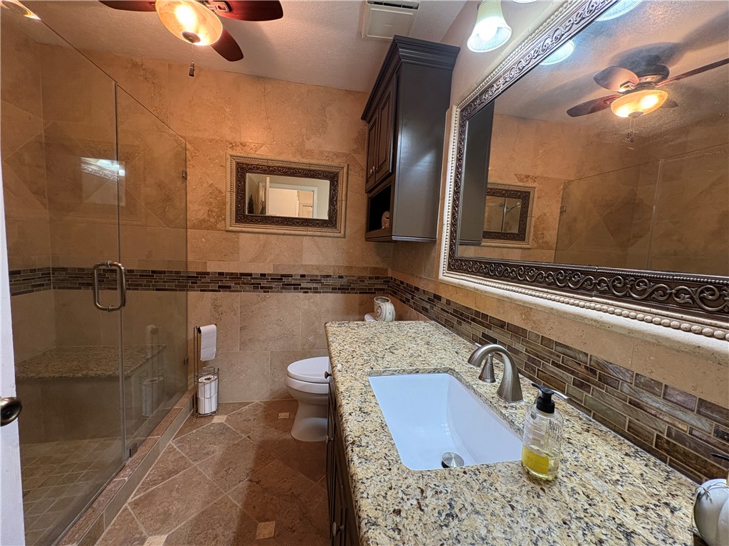 1501 Maple Drive Bryan, TX 77803 - Photo 8 of 19 a bathroom with a granite countertop sink a mirror and a toilet