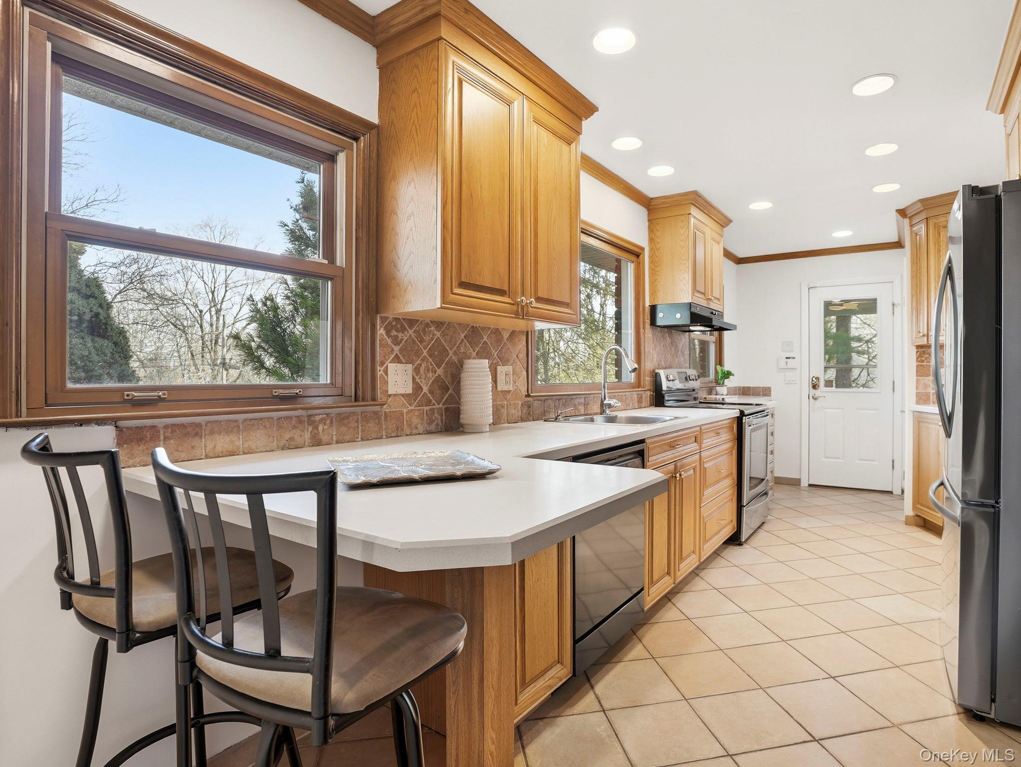20 Highview Road Ossining, NY 10562 - Photo 13 of 28 Kitchen featuring crown molding, stainless steel appliances, light countertops, a peninsula, and light tile patterned floors