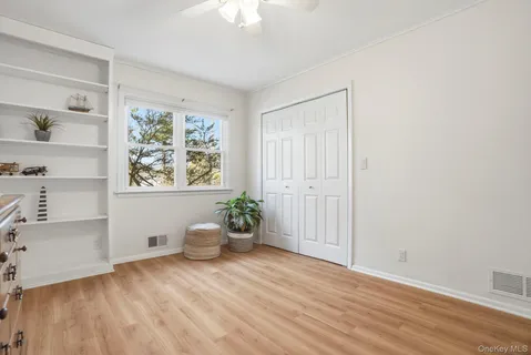 a view of empty room with wooden floor and fan