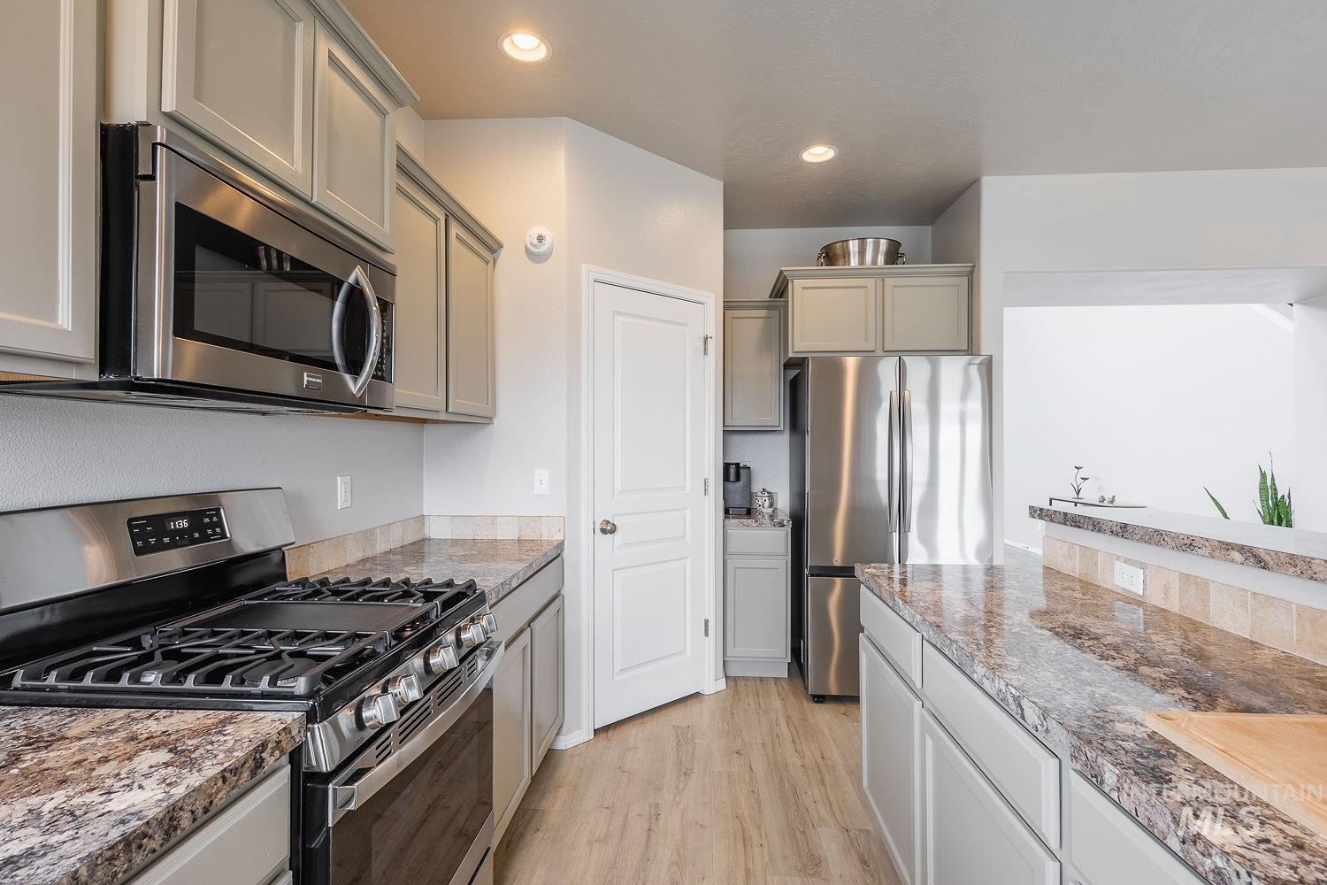 2515 Fallcrest Street Caldwell, ID 83607 - Photo 13 of 48 Kitchen featuring stainless steel appliances, light wood-style floors, gray cabinetry, recessed lighting, and dark stone counters