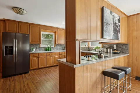 a kitchen with stainless steel appliances granite countertop a stove a sink dishwasher and a microwave oven with large wooden cabinets