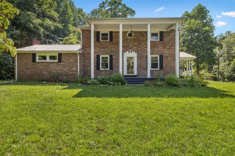 a view of a house with a backyard and a park