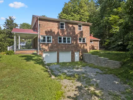 a view of a house with a big yard and large trees