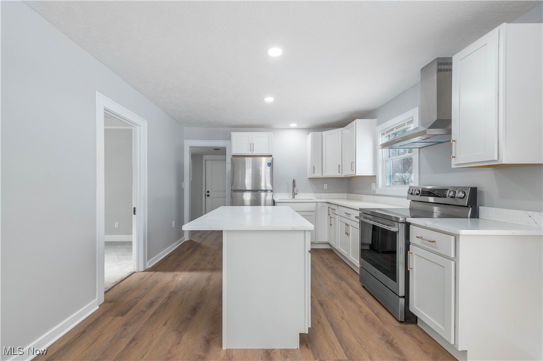 218 Roxboro Road Vermilion, OH 44089 - Photo 13 of 50 Kitchen with stainless steel appliances, wall chimney exhaust hood, a center island, white cabinets, and dark wood-type flooring