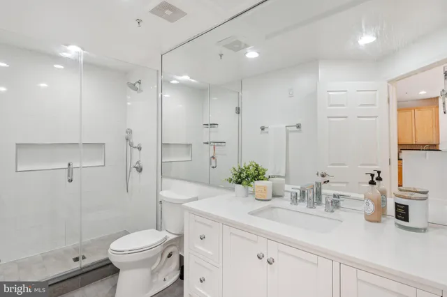 a bathroom with a granite countertop sink a toilet and shower
