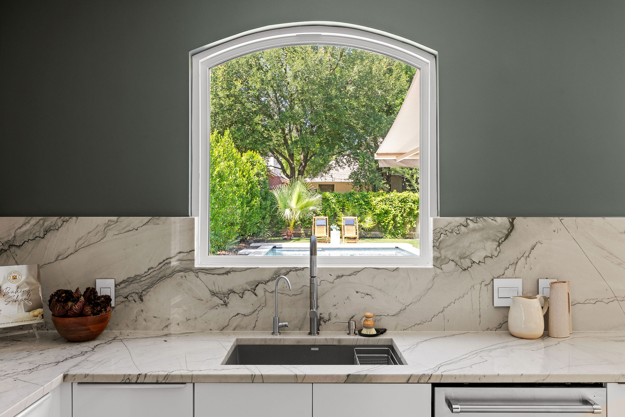 6500 Clay Allison Pass Austin, TX 78749 - Photo 16 of 39 Kitchen sink workstation featuring an arched window, full-height veined backsplash, and integrated dishwasher