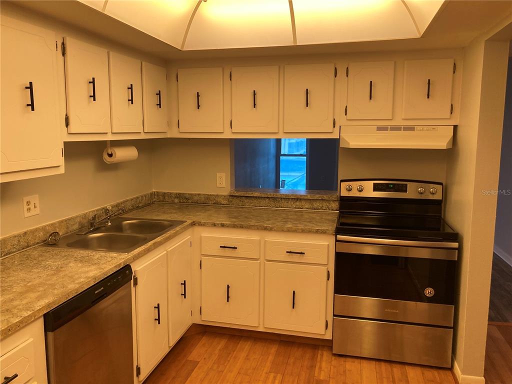 4908 38th Way South, Unit 303 St. Petersburg, FL 33711 - Photo 2 of 14 a kitchen with granite countertop white cabinets and stainless steel appliances
