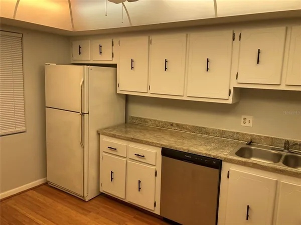 a kitchen with appliances cabinets and a wooden floor
