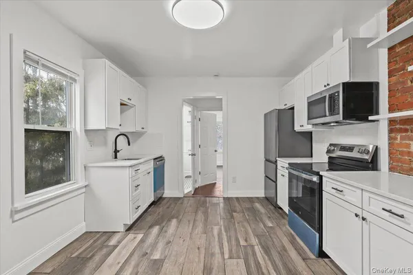 a kitchen with a sink wooden floor and stainless steel appliances