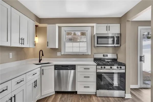 a kitchen with cabinets appliances a sink and a window