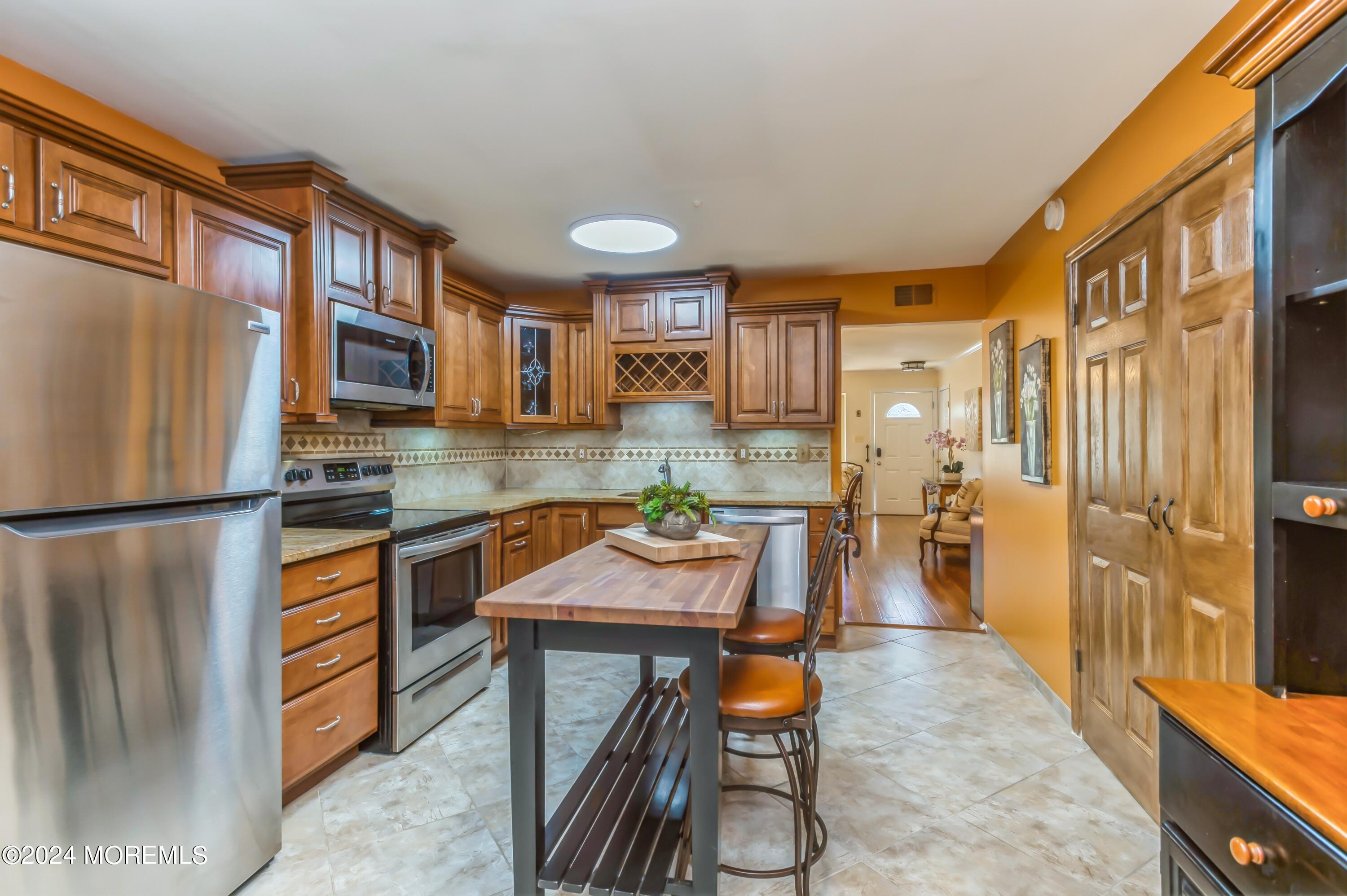 147 B Cours De Pasteur, Unit 1000 Freehold, NJ 07728 - Photo 11 of 28 a kitchen with a refrigerator a stove top oven a sink and dining table