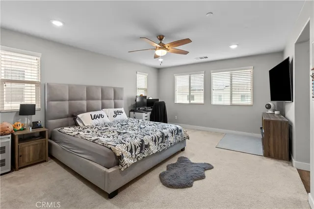 a spacious bedroom with a bed and a flat screen television