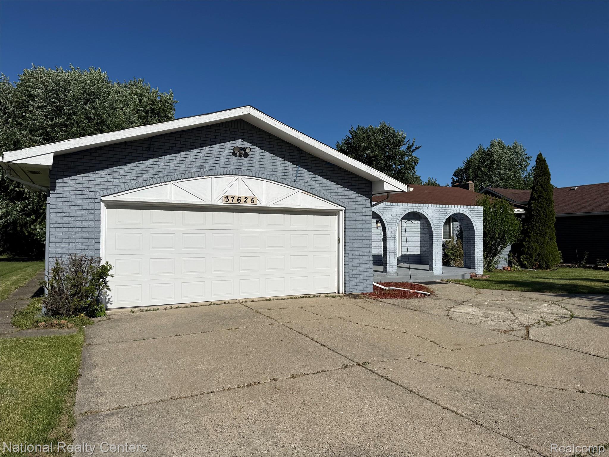 37625 Ryan Road Sterling Heights, MI 48310 - Photo 3 of 30 Exterior featuring a light blue brick facade, white garage door, and a covered entryway with arch details