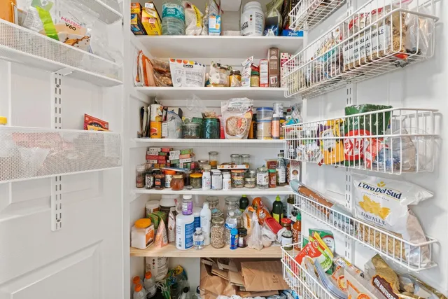 a utility room with stainless steel appliances lots of clutter and refrigerator