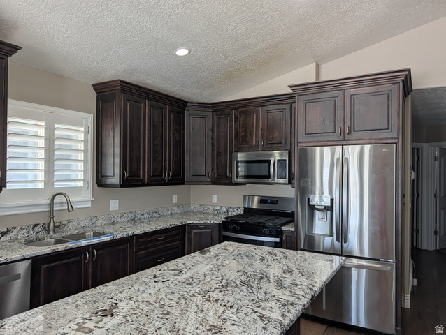 171 South Mustang Road East Grantsville, UT 84029 - Photo 7 of 41 Kitchen featuring dark wood cabinetry, light-toned stone countertops, and stainless steel appliances