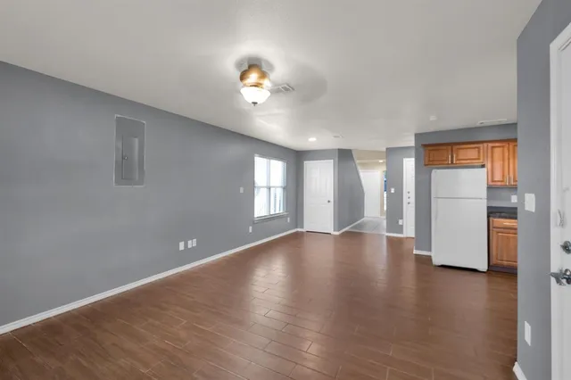 a view of an empty room with window and wooden floor