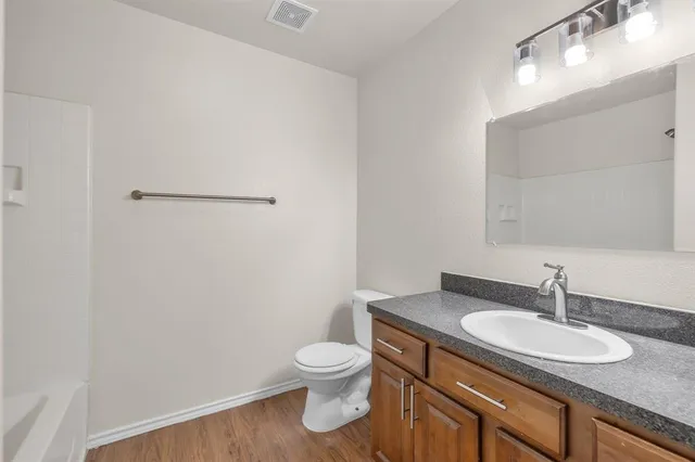 a bathroom with a granite countertop sink toilet and a mirror