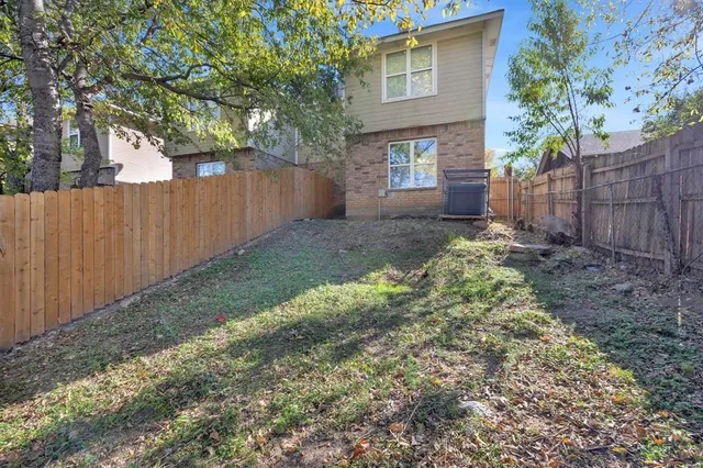 a view of a backyard with wooden fence and a large tree