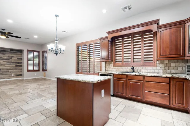 a kitchen with granite countertop stainless steel appliances a sink counter space cabinets and a chandelier