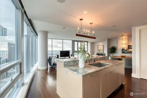 a living room with kitchen island granite countertop a large window cabinets and stainless steel appliances
