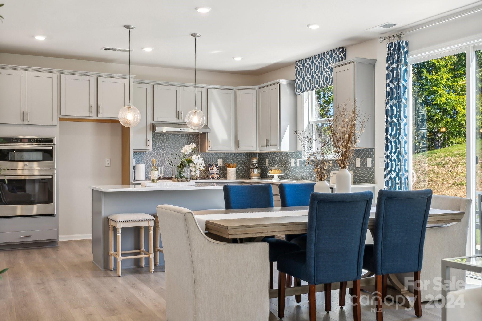 1406 Hubert Graham Way Tega Cay, SC 29708 - Photo 22 of 26 a kitchen with granite countertop a table chairs microwave and cabinets