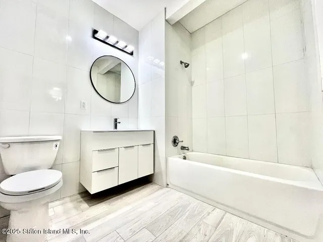 a bathroom with a toilet a sink a mirror and bathtub