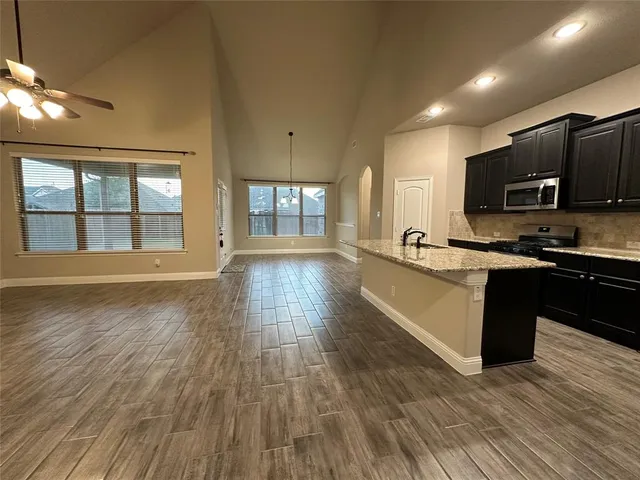 a large kitchen with stainless steel appliances granite countertop a stove and a wooden floors