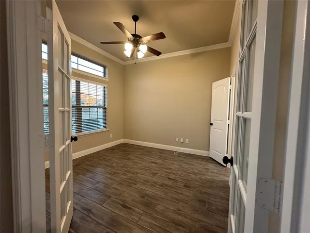 an empty room with wooden floor and ceiling fan