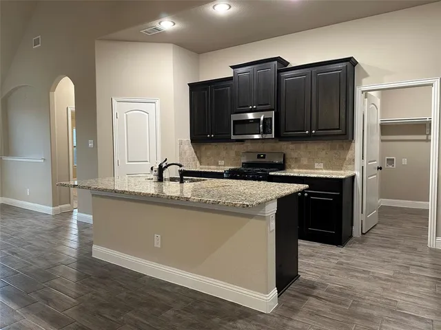 a kitchen with stainless steel appliances granite countertop a stove a sink and a microwave