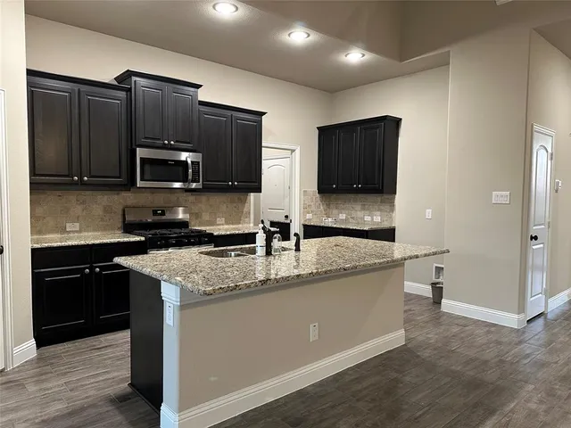 a kitchen with stainless steel appliances wooden cabinets a sink and a stove