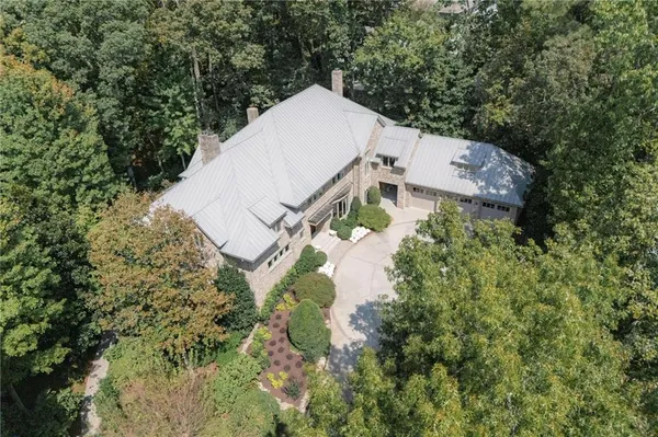 an aerial view of residential house with outdoor space and trees all around